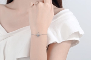 Detail of S925 silver bow bracelet with light blue stone on model wrist
