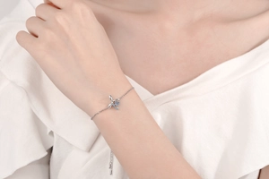Close-up of S925 sterling silver bow bracelet with blue moissanite on female wrist