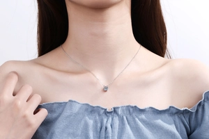 Élégant pendentif solitaire en argent 925 porté sur un chemisier en soie bleu clair