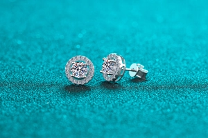 Macro shot of round halo moissanite stud earrings in S925 sterling silver on blue glitter