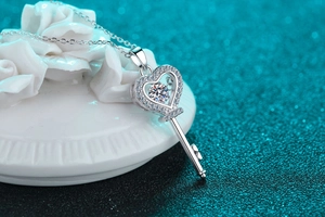 Makroaufnahme von Herz-Schlüssel-Anhänger mit Moissanit-Diamant auf weißer Rose