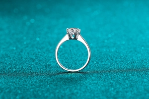 Macro shot of 1-carat moissanite ring with classic six-prong setting on a glittery background