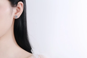 Close-up of round halo moissanite stud earrings in S925 sterling silver worn by a model