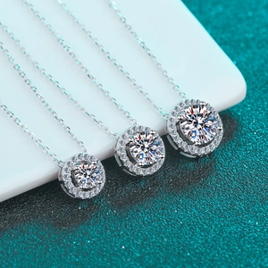 Trois colliers en argent 925 avec pendentifs moissanite de tailles variées sur fond vert