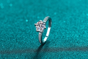 Macro shot of crown moissanite ring with six-prong setting and side diamonds on glittery background