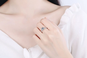 Detailed view of a crown-style silver moissanite ring with side diamonds on a finger