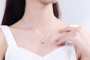 Close-up of S925 silver lucky cat necklace with dancing moissanite on female collarbone