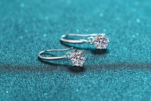 Macro shot of S925 sterling silver six-prong moissanite earrings on blue background