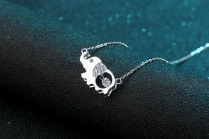 Macro shot of silver elephant pendant with dancing moissanite stone and pave details