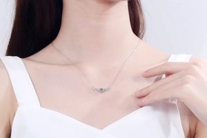 Close-up of S925 sterling silver angel wing necklace with sparkling moissanite on a model