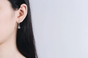 Close-up of S925 sterling silver drop earring with round moissanite worn by a model