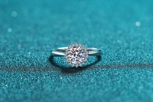 Macro shot of S925 silver sunflower ring with moissanite center on teal glitter background