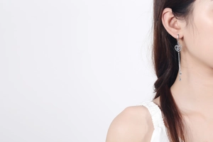 Macro shot of silver heart tassel earring with moissanite crystals on a female model