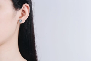 Macro detail of a 1ct moissanite round stud earring with halo setting worn by a model