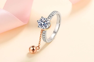 Detail of silver moissanite ring with rotating rose gold chain and spherical pendant