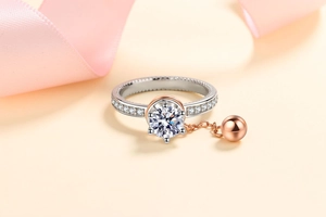 Detail of S925 silver ring with a large moissanite center stone and rose gold bead charm