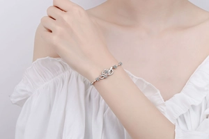 Détail d'un bracelet fleur bicolore avec pavé de cristaux sur un poignet de femme