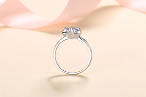 Detailed close-up of heart-shaped prong setting with a purple moissanite stone