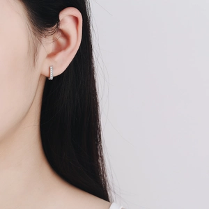 Boucles d'oreilles huggie en argent S925 avec moissanite portées par un mannequin femme