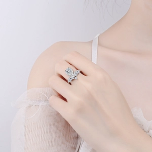 Close-up of a pear-cut moissanite halo ring with delicate vine-like silver band detailing