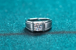 Macro detail of men's silver ring showing matte texture and four-prong moissanite setting