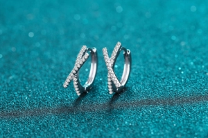 Macro detail of silver S925 sterling silver hoop earrings with crisscross pavé moissanite