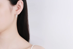 Detailed view of silver triangle drop earrings with pavé stones on a model