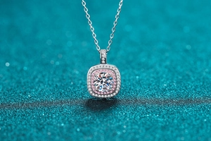 Macro detail of square halo pendant necklace with white and pink stones on green background