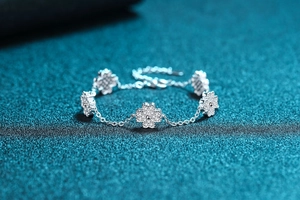 Macro shot of 925 silver four-leaf clover bracelet with pave moissanite on blue background