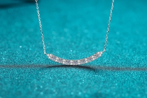 Macro shot of silver smile necklace showing brilliant pavé moissanite stones and craftsmanship