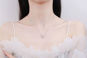 Détail du collier argenté en V avec pierres scintillantes sur le cou du mannequin