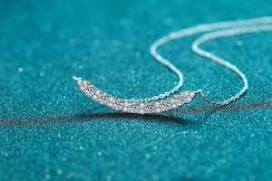 Macro shot of silver smile necklace pendant with pavé set moissanite stones and fine chain
