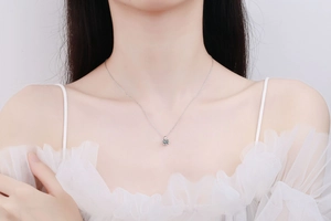 Close-up of minimalist S925 silver necklace with round moissanite pendant on female model