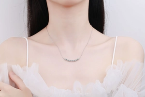 Close-up of 925 sterling silver smile necklace with moissanite pavé worn by a model