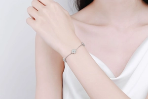 Detail of 925 sterling silver four-leaf clover bracelet on model's wrist with micro-inlay