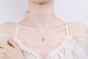 Close-up of S925 silver clover pendant necklace with moissanite on a female model