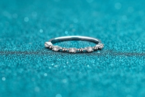 Macro detail of silver ring with five round moissanite stones and beaded metal accents
