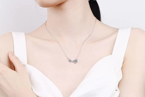 Détail du collier en argent S925 avec pendentif croisé et moissanite bleue sur mannequin