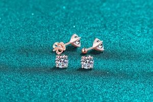 Macro detail of rose gold moissanite stud earrings with butterfly and ball screw backings