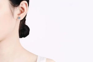 Detailed macro view of 925 silver moissanite stud earring on ear with classic four-prong setting