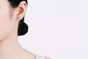 Detail of S925 sterling silver reindeer stud earring with light blue zircon on model ear