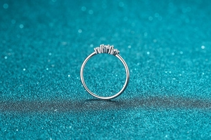 Detailed close-up of S925 sterling silver ring with pavé moissanite stones on blue glitter