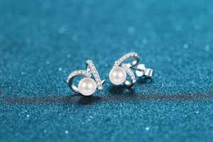 Détail macro d'une boucle d'oreille en argent courbée avec zircons et perle d'eau douce