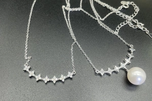 Macro detail of S925 silver four-pointed star necklace set with pearl and zircon charms