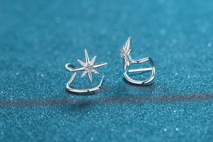 Macro detail of 925 silver star-shaped ear cuff with sparkling moissanite on blue background