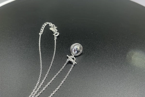Detail of silver necklace with hollow round pendant and heart-shaped adjustable clasp