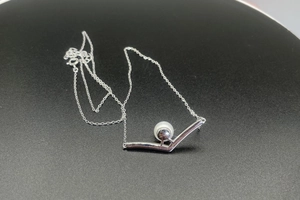 Macro detail of S925 silver V-shaped pendant with an 8mm freshwater pearl on a thin chain