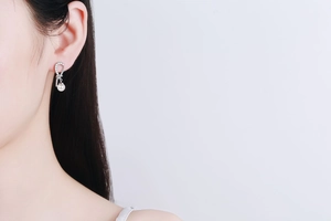 Elegant asymmetrical silver earrings with freshwater pearls and pavé stones on model