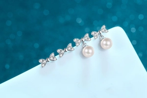 Macro detail of bow-shaped S925 silver earrings with sparkling stones and white pearl