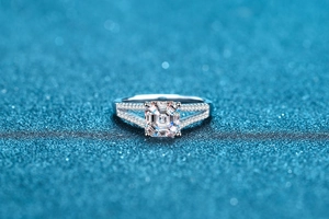 Macro shot of Asscher cut moissanite ring with micro-paved band on starry blue background